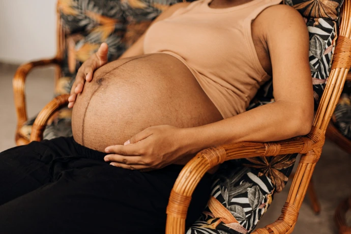 a pregnant woman sitting in a wicker chair